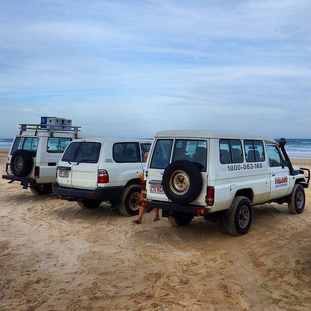 land vehicle, transportation, mode of transport, sky, car, sand, beach, stationary, cloud - sky, parking, travel, parked, day, street, outdoors, road, cloud, sunlight, sea, shore