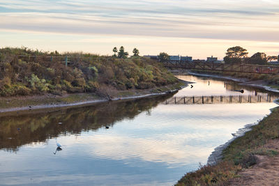 Arch bridge over river against sky during sunset