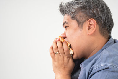 Close-up of man eating food against white background