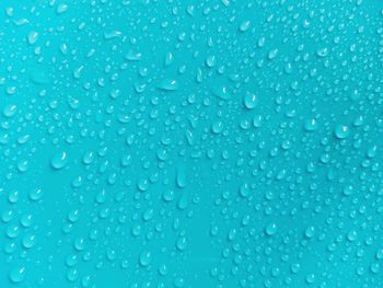 Full frame shot of wet glass against blue background