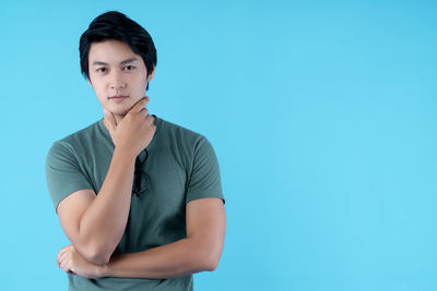 Portrait of young woman standing against blue background