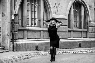 Portrait of senior woman wearing hat on walkway against building