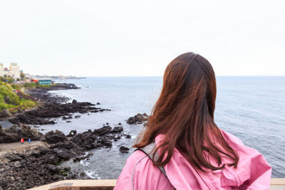 Rear view of woman looking at sea shore against sky