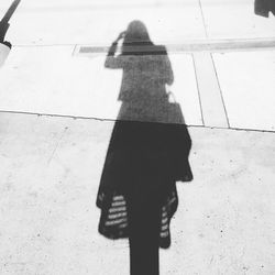 Shadow of man on woman holding umbrella