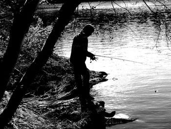 Silhouette of man fishing in lake