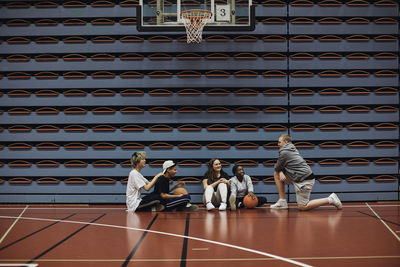 Smiling boys and girls talking with each other at basketball court in school