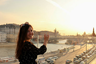 Portrait of young woman standing against sky during sunset