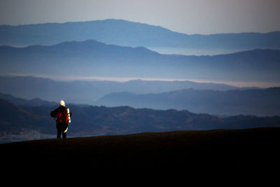 Silhouette man standing on mountain against sky