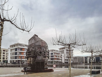 Statue in city against cloudy sky