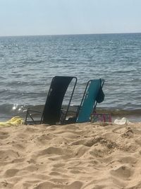 Deck chairs on beach against clear sky