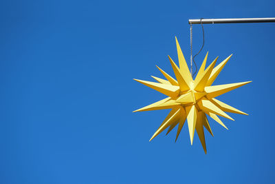 Low angle view of star shape against clear blue sky