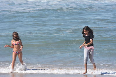 Full length of siblings standing on beach