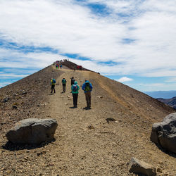 Rear view of people walking on road against sky