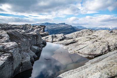 High angle view of rocky mountain against cloudy sky