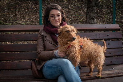 Portrait of woman with dog sitting on bench