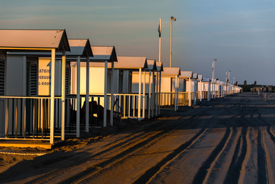 Railroad tracks by buildings against sky during sunset