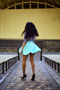 Rear view full length of young woman walking on footpath at amphitheater