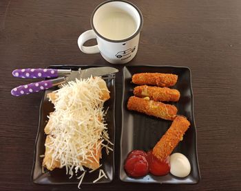 Fried banana with mozzarella topping and mozzarella nuggets and a glass of hot milk