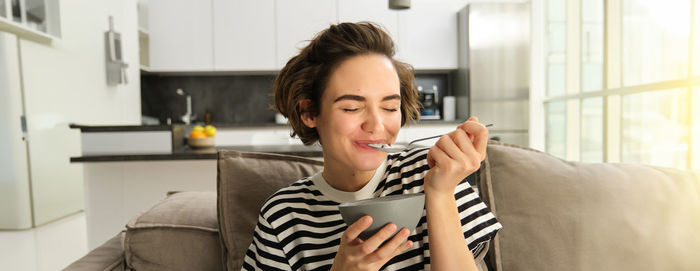 Young woman using mobile phone while sitting on sofa at home