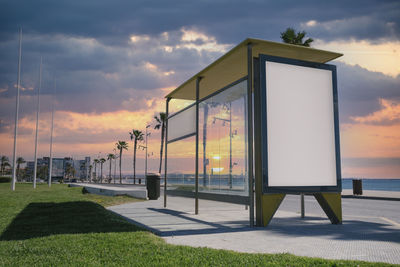 Blank advertisement in a bus stop, next to the sea at sunrise.