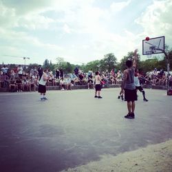 Group of people playing soccer on field against sky