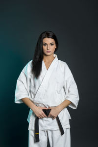 Portrait of karate woman standing against black background