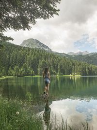 Rear view of woman standing amidst lake