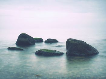 Rocks in sea, long exposure makes moody soft water level. melancholy blue mood