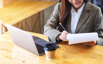 Midsection of woman using digital tablet on table