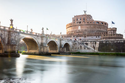 Arch bridge over river against sky in city