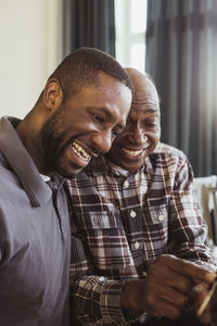 Happy elderly man pointing by male caregiver at nursing home