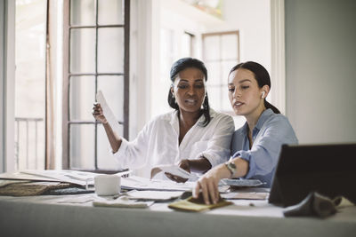 Female architects discussing while working at table in home office