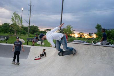 Group of people skateboarding on road against sky