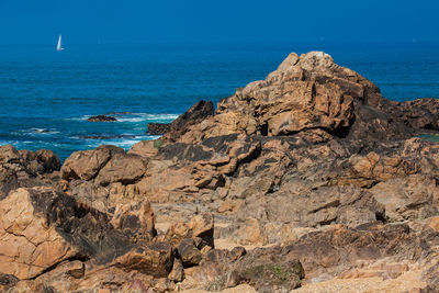 Rock formation on beach against clear blue sky