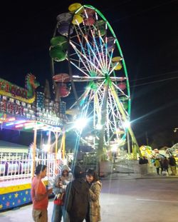 People in illuminated ferris wheel at night