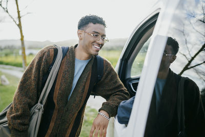 Smiling young man leaning van