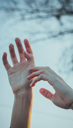 Close-up of hands against sky