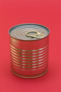 Unopened tin can with blank edge on red background