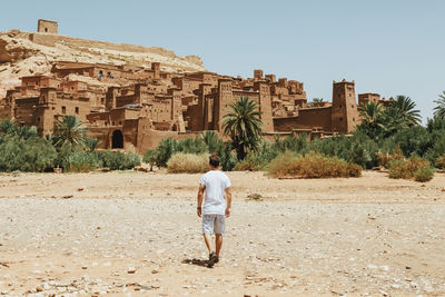 Rear view of man walking towards historic building against sky