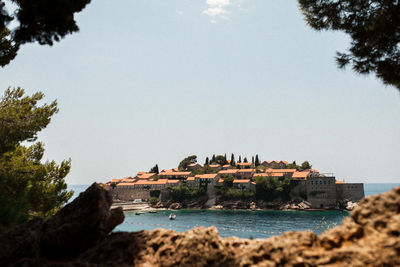 Buildings by sea against clear sky