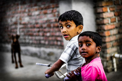 Portrait of siblings riding bicycle on street