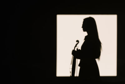 Side view silhouette female violinist standing with musical instrument and thoughtfully looking away