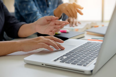 Close-up of woman using laptop on table
