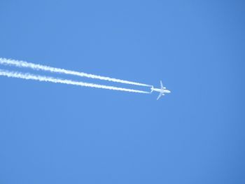 Low angle view of airplane flying against clear blue sky