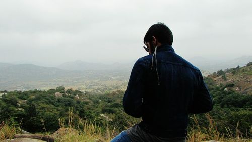 Rear view of man standing on landscape against sky