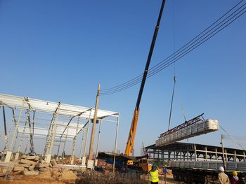 Low angle view of cranes against sky