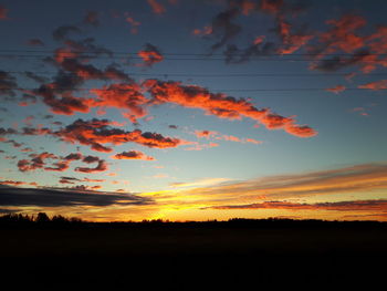 Silhouette landscape against dramatic sky during sunset