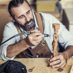 Carpenter carving on figurine in workshop