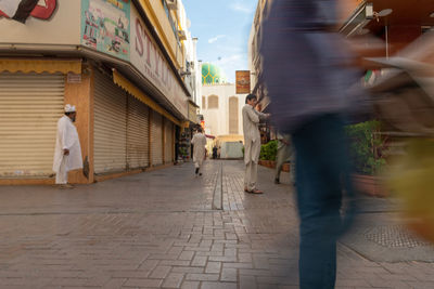 Rear view of people walking on street amidst buildings