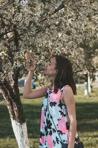 Midsection of woman standing by cherry tree